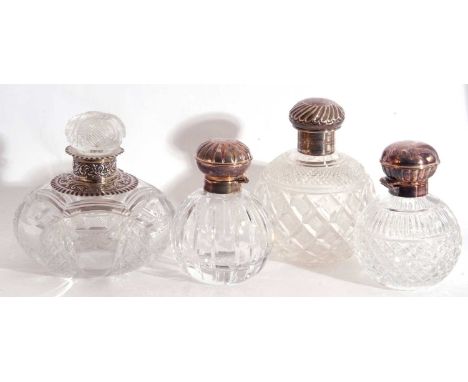 Group of four cut glass table scent bottles to include a Victorian large bottle with silver neck and collar, London 1889, mak