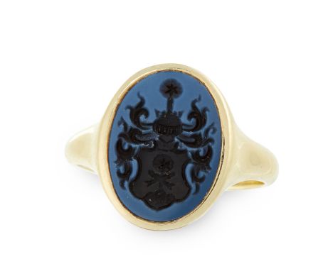 AN ANTIQUE CARVED HARDSTONE INTAGLIO SEAL / SIGNET RING in yellow gold, set with an oval banded hardstone, reverse carved in 