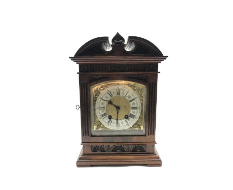 Late 19th century mantle clock in architectural walnut case, arched pediment with central leaf carved motif, enclosed by beve