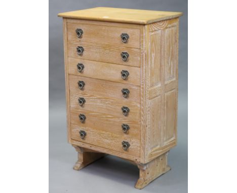 A limed oak small upright chest fitted seven long drawers with iron ring handles, having fielded panel sides, &amp; on shaped