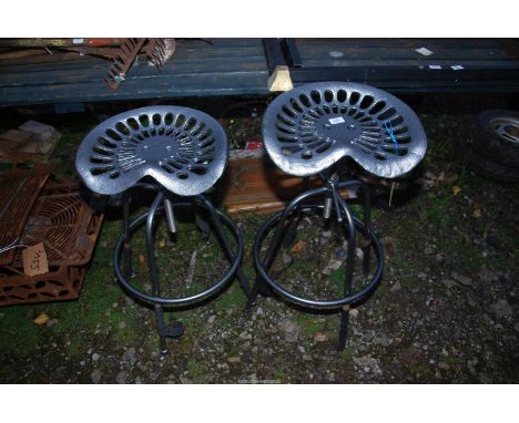 A pair of adjustable bar stools with tractor style seats.