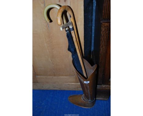 A copper boot stick stand with 2 sticks and a umbrella.