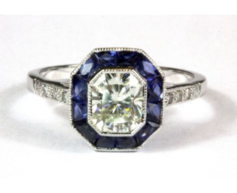 An 18ct white gold (stamped 18k) diamond and sapphire set halo ring,  centre diamond (N).