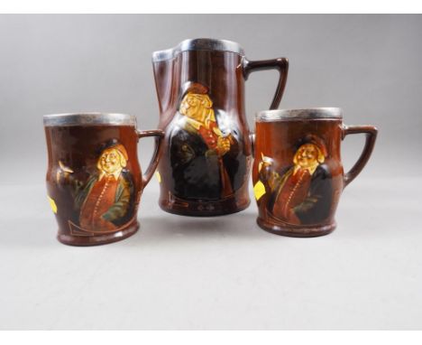 A Royal Doulton silver topped Charles Noke pitcher and a matching pair of tankardsCondition:One mug and the pitcher do not ri
