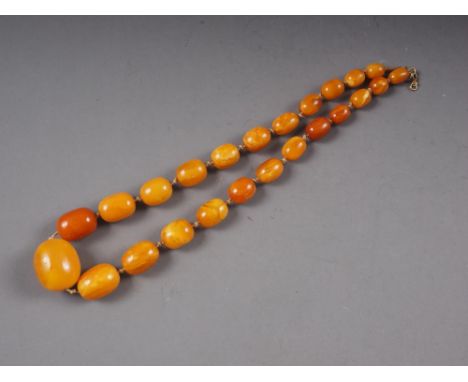 An Art Deco butterscotch/egg yolk amber graduated bead necklace, the largest oval bead 19mm wide, total weight 50.8gCondition