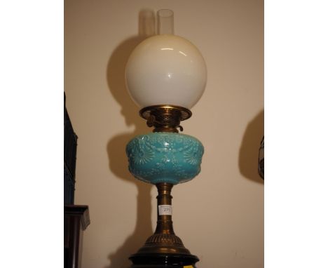 A late 19th century brass oil lamp with milk blue glass reservoir decorated mask, flower and swags and milk glass shade, on c