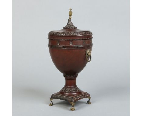 A 19th century Neo-Classical carved mahogany urn shaped tea caddy. With brass finial, lion mask handles and raised on four ba