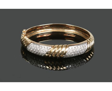 A 14 carat gold bangle, reeded and with two pave set diamond panels, gross weight 38.9 grams, 6.75cm. Condition Report. To be