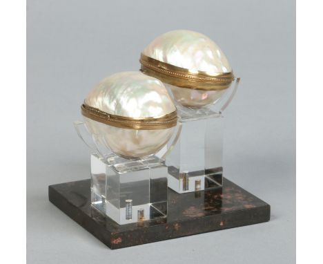 A pair of mother of pearl and gilt metal mounted hinged boxes raised on a Perspex and marble stand, boxes 8.25cm. Condition R