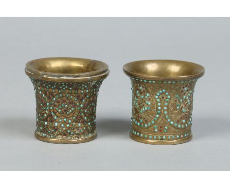 Two 19th century Indian brass beakers of flared form and with turquoise and garnet jewelled decoration, 6.25cm. Condition Rep