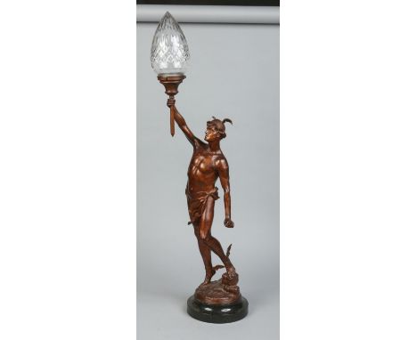 A large figural bronzed spelter lamp. Modelled in Classical form as Mercury holding a torch with a cut glass shade and raised