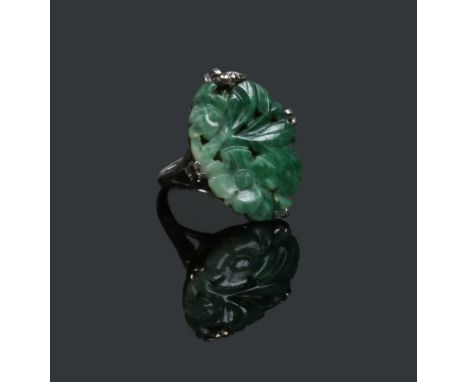A white metal ring set with a carved and pierced ovoid jade tablet, size L. Condition Report. To be used as a guide only. Goo