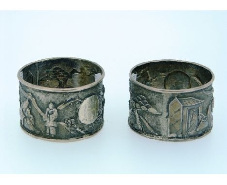 A pair of late 19thC Chinese silver Napkin Rings, by Woshing, Shanghi, chased with figures and trees, monogrammed, 1¾in (4.5c