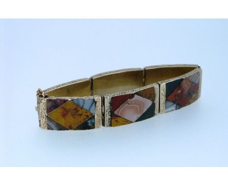 A Scottish pebble hinged six plaque Bracelet, each plaque mounted in engraved gilt metal and each centre with diamond set col