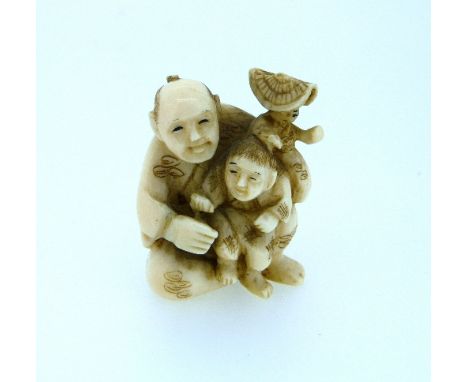 A 19thC Japanese carved ivory Netsuke, of a father seated holding a child with a doll on his shoulder, signed, 1½in (3.75cm) 