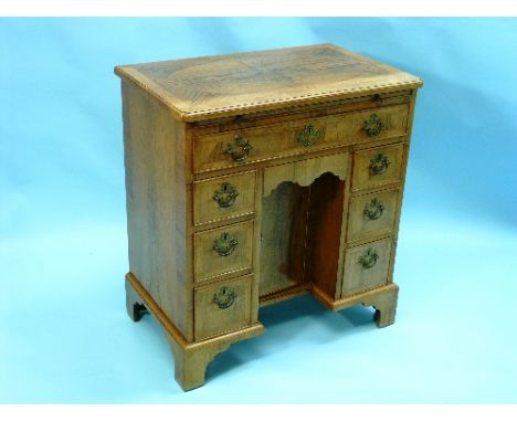 A Georgian-style walnut Kneehole Desk, with cross-banded and feather-banded decoration, the rectangular quarter veneered top 