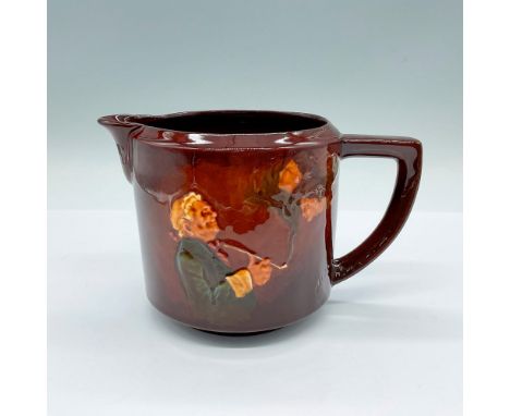 A brown glazed pitcher featuring a man smoking a long pipe. Two faces are seen in the smoke. Inscribe on the other side: Happ