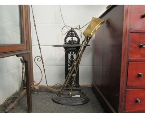 A Victorian cast iron stick stand, a three piece set of brass fire irons and a pair of 19th Century brass doorstops in the fo