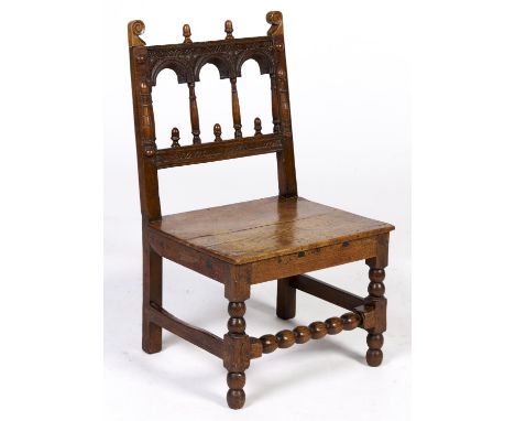 An oak chair, 17th c and later, the arcaded back with acorn and scroll finials, applied split baluster turnings, on bobbin an