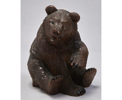 A Swiss carved and stained limewood sculpture of a bear, c1900, seated on his haunches with alert expression and left fore pa