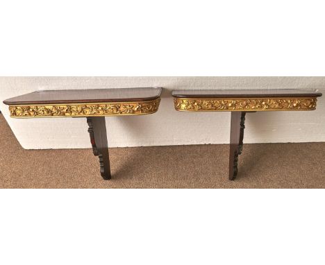 A pair of parcel gilt mahogany console tables, 20th c incorporating 19th c elements, with crisply carved leaf and scroll brac