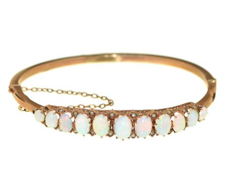 An opal and split pearl bangle, early 20th c, in gold, 81mm, marked 9ct, 6g Dented and worn, opals retaining good polish, one