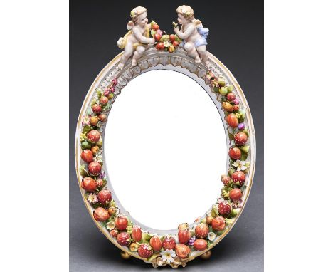 A German porcelain dressing mirror, late 19th c,&nbsp; the oval frame encrusted with strawberries and other fruit and flowers