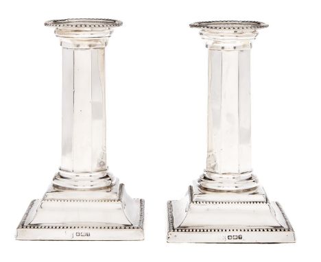 A pair of George V silver dwarf columnar candlesticks, on beaded square foot, nozzles, 13cm h, by George Edward &amp; Sons, S