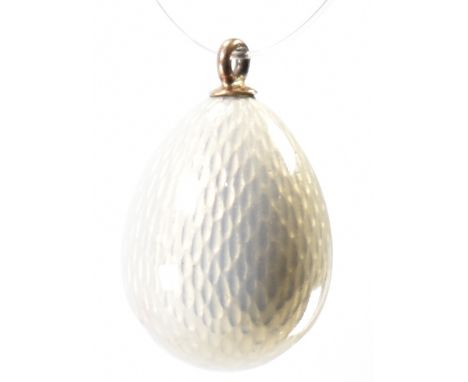 A Russian gold guilloche enamel egg pendant.  The pendant in the form of an egg having white enamel decoration with gold bale