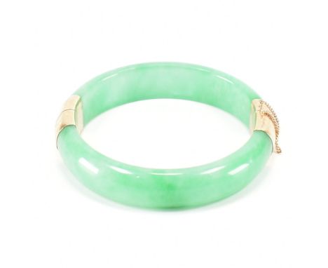 A vintage green jade and gold plated bangle bracelet. The bracelet having gold plated fittings with a tongue in groove clasp.