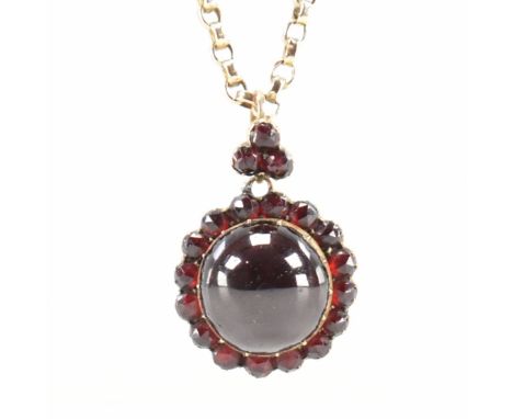 An antique garnet locket on a gold chain. The Victorian locket being set with central garnet cabochon surrounded by a halo of