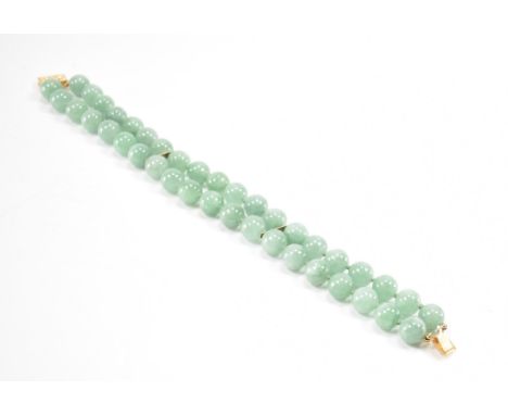 A vintage gold and jade beaded bracelet. The bracelet having two rows of round jade beads having a rectangular box clasp. The