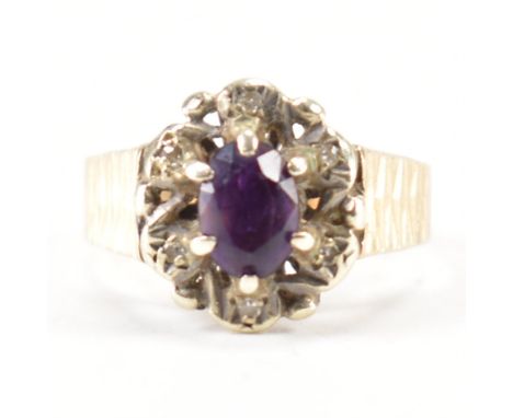 A hallmarked 9ct gold and amethyst ring. The ring being set with an oval cut purple stone to the centre with a halo of white 