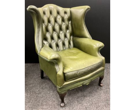 A Green leather wingback armchair, deep button back, cabriole legs, 106cm high x (43cm to seat) x 86cm wide x 74cm deep.