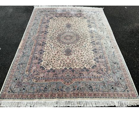 A Large Oriental wool and silk mix rug / carpet, knotted in tones of pale jade green, pink, and cream, 351cm x 258cm.