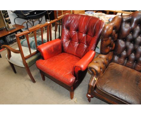A red button backed upholstered armchair