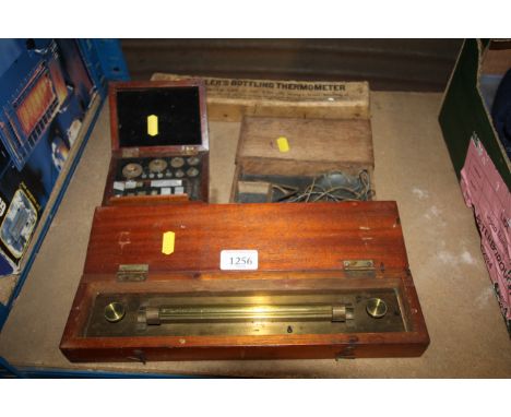 A wooden boxed brass measuring scroll, a wooden cased balancing travel set of scales, a wooden cased set of scale weights and