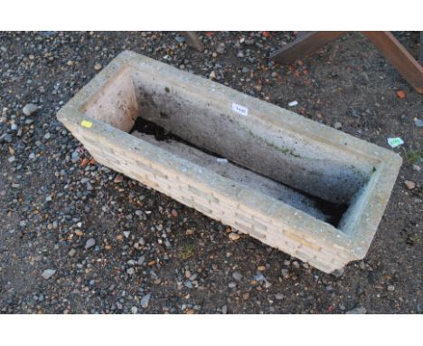 A cast concrete garden plant trough with brick styled outer