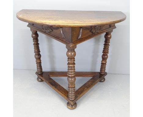 An early 20th century mahogany demi-lune console table, with applied carved swag decoration and raised on bobbin-turned legs.