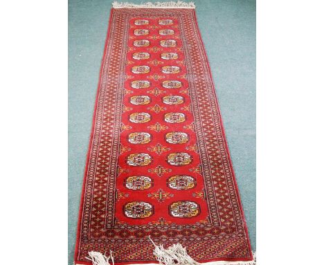 GOOD QUALITY PAKISTAN BOKHARA RUNNER. With two rows of guls on a crimson field with  diaper pattern border with guards stripe