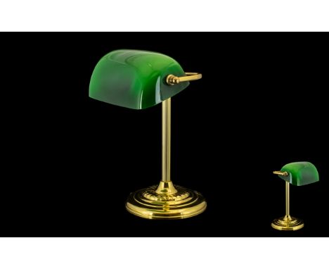A Brass Desk/Bankers Lamp with green polished shade raised on a circular base. Measures 14 inches in height.
