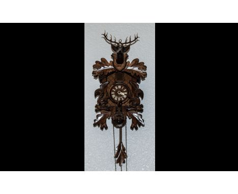 Black Forest Carved Cuckoo Clock of traditional form, front carved with squirrels, surmounted by a carved stag's head, with t