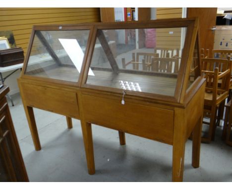 A vintage oak retailer's display cabinet with top section in glazed triangular format, the base with two drop flaps revealing