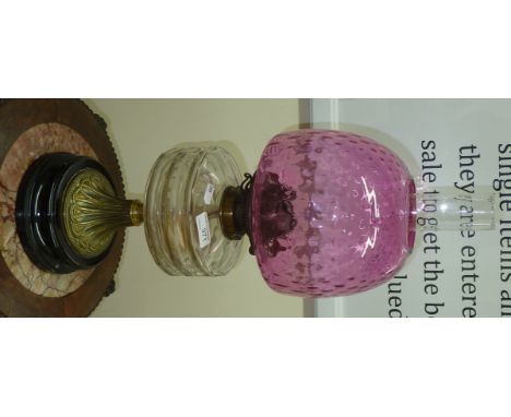 Large Victorian oil lamp with clear glass reservoir and cranberry shade