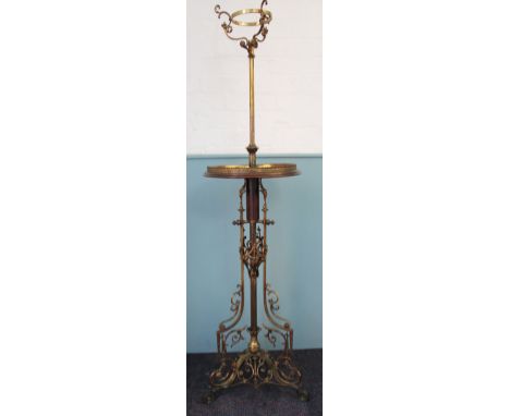 A Victorian lacquered brass adjustable oil lamp standard, with scroll top above a circular walnut shelf, on triform base with