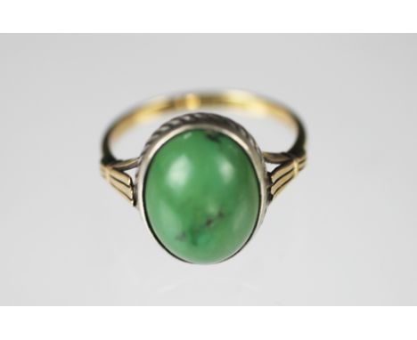 A jade set ring, the oval cabochon jade within white metal surround and yellow metal 'fan' shoulders and plain hoop, stamped 