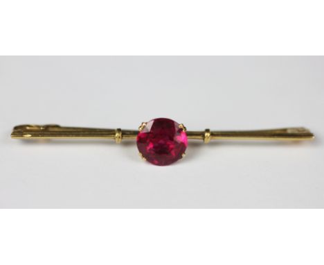 A ruby doublet set bar brooch, the central stone (measuring 10mm diameter), claw set in yellow metal (unmarked), weight 3.6gm