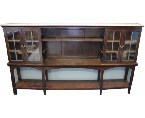 A late Victorian Arts and Crafts oak low bookcase cabinet, with shelf centre section flanked by lead glazed doors enclosing s