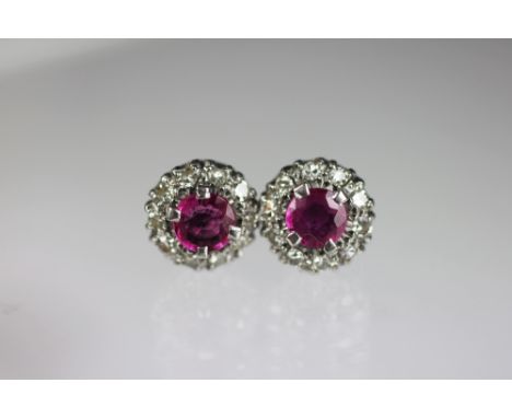 A pair of ruby and diamond cluster earrings, the central circular ruby within a surround of eleven, 8 cut diamonds, all claw 