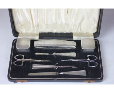 A George V silver manicure set, with engine turned detailing, comprising two boxes, nail buff, file, two implements, the stee